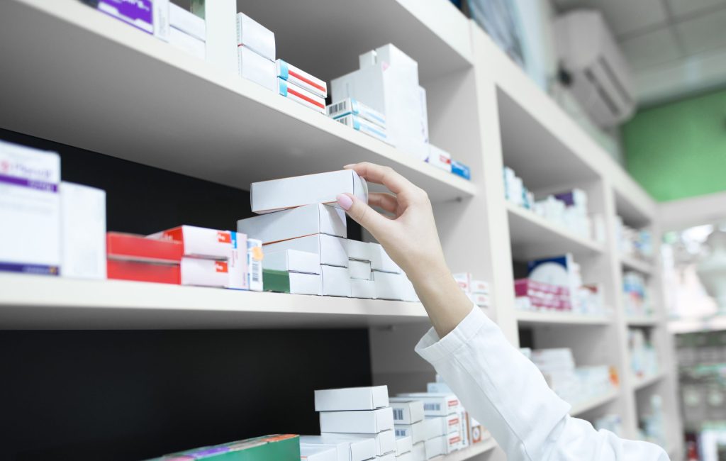 closeup-view-pharmacist-hand-taking-medicine-box-from-shelf-drug-store-1-scaled